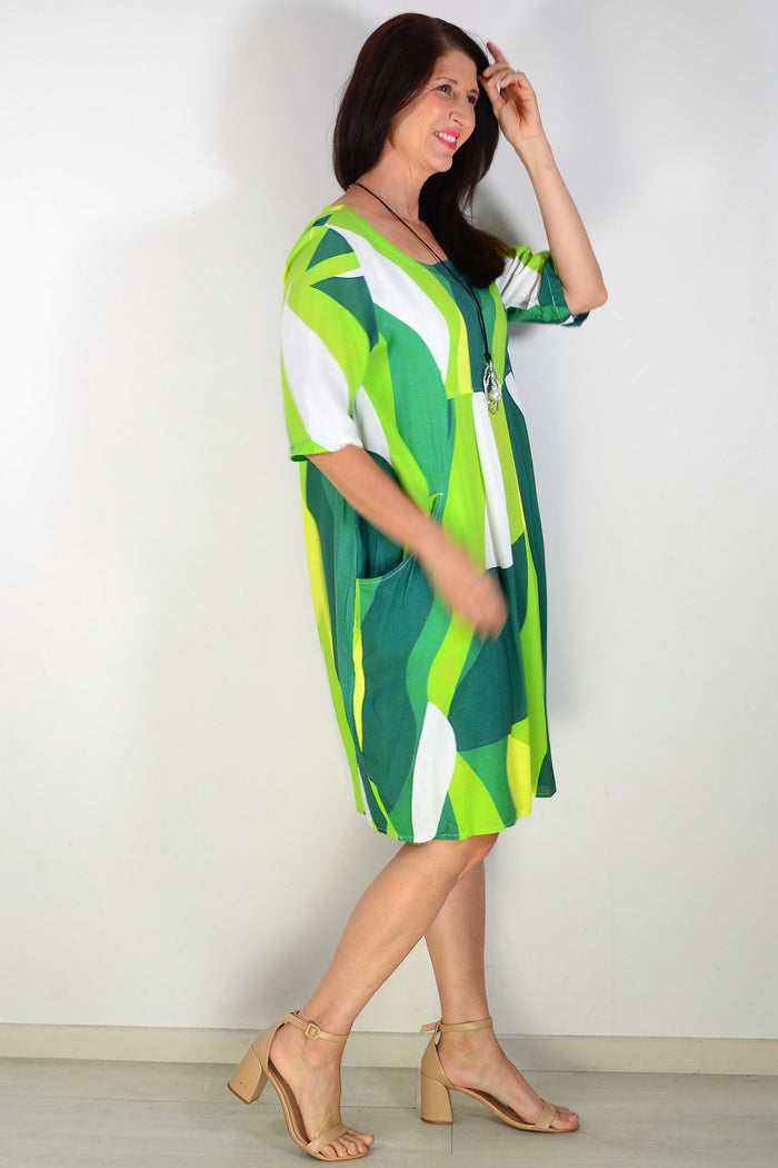 Green and white abstract print Hourglass tunic dress hanging on a display with a flowing fabric design.