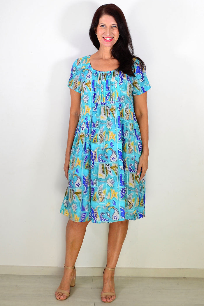 Hourglass aqua paisley floral tunic dress with pleated design, featuring a casual, flowy silhouette and vibrant pattern.