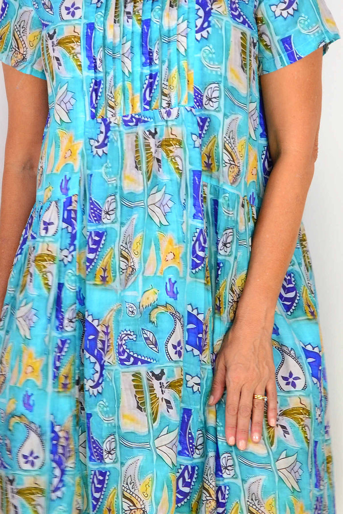 Hourglass aqua paisley floral pleated casual tunic dress displayed on a hanger, showcasing its flowy fabric and vibrant pattern.