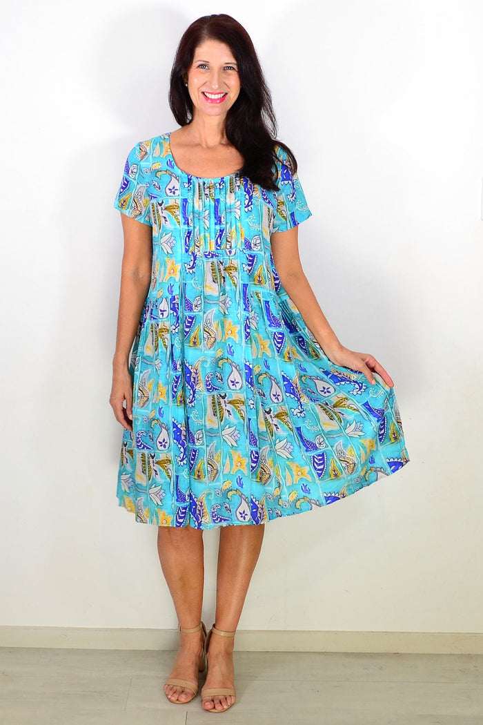 Hourglass Aqua Paisley floral pleated casual tunic dress hanging on a mannequin with a relaxed fit and vibrant pattern.