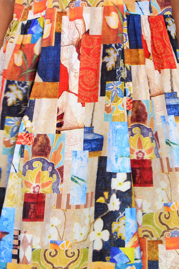 Hourglass artisan mosaic pleated casual tunic dress with intricate patterns and flowing fabric, displayed on a hanger.
