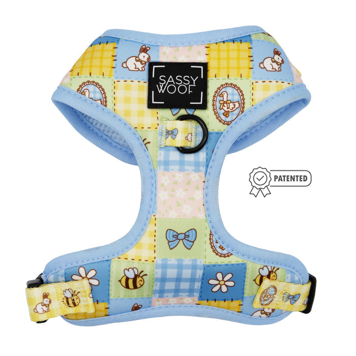 The Sassy Woof Dog Adjustable Harness - Patch Perfect features colorful patchwork with pastel blue trim, bunnies, bees, bows, and flowers. Ideal for growing puppies, it includes a patented badge.