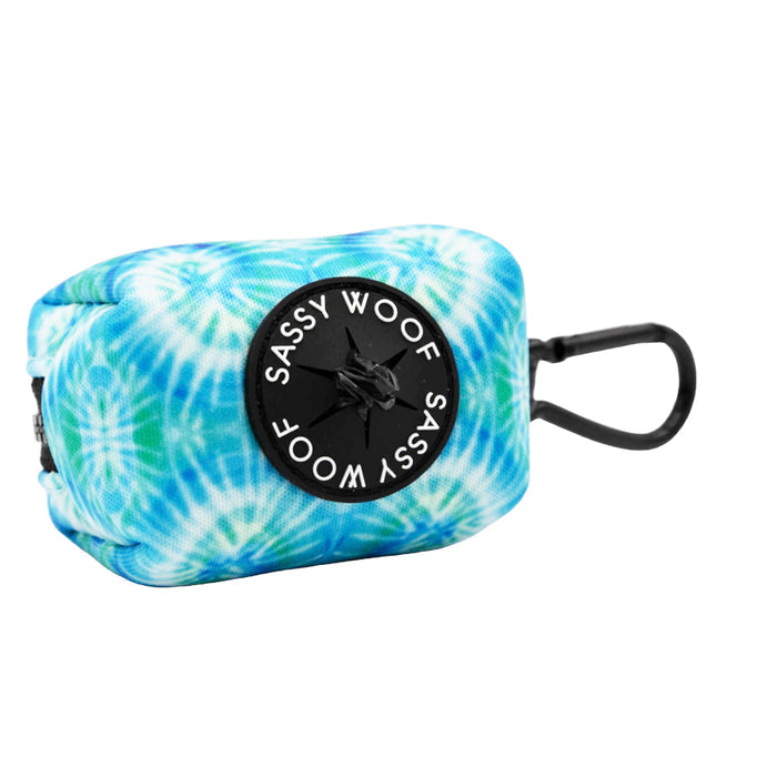 The Sassy Woof Dog Waste Bag Holder - Tropical Tides is a small neoprene blue and white tie dye holder with a black clip and circular dispenser—a stylish, tropical accessory for your pup.