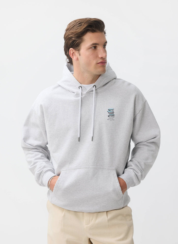 A model wears the grey cotton Duke Hoodie by Percival, an oversized sweatshirt with a hand-drawn graphic on the chest.