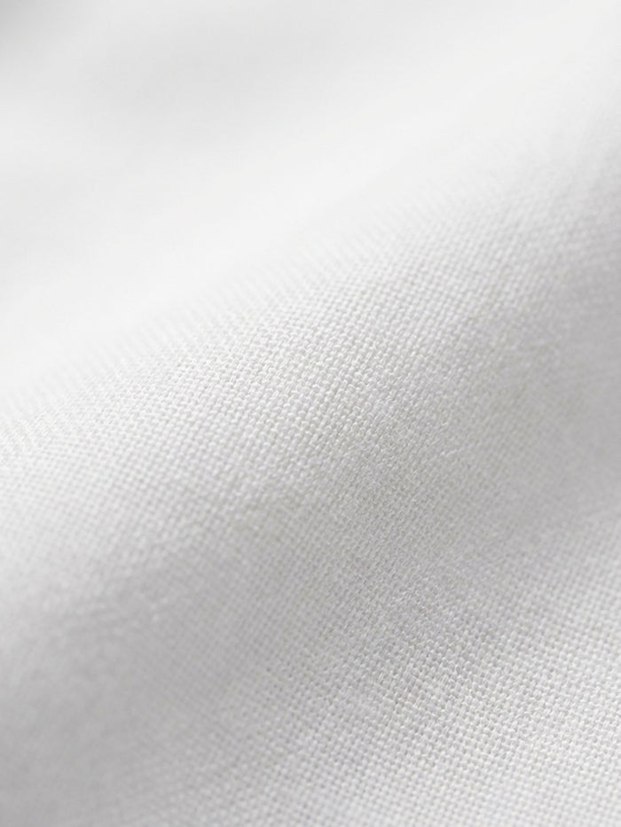 Close-up of white shirt fabric showing smooth weave and premium cotton texture.