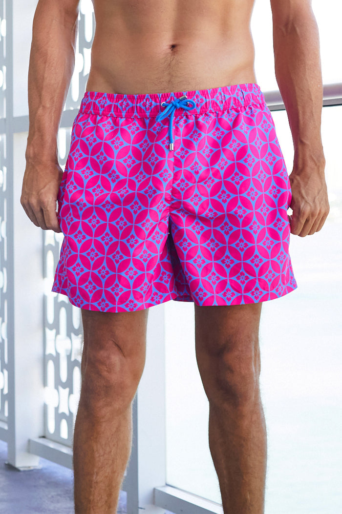 Close-up of a man wearing bright pink and blue patterned swim shorts with a drawstring waist.