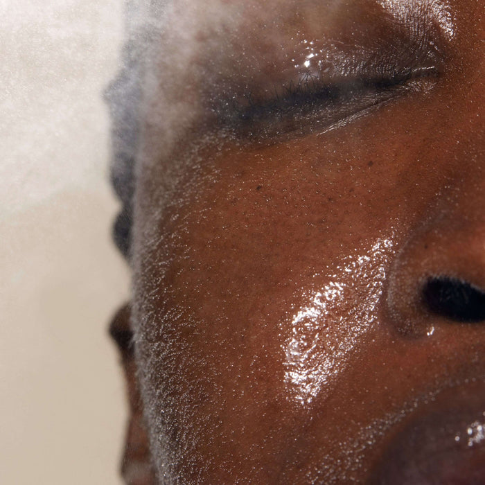 Close-up of a person with dewy skin and closed eyes as they spray Queen of Hungary Mist | Omorovicza, highlighting a refreshing moment of skincare and hydration.