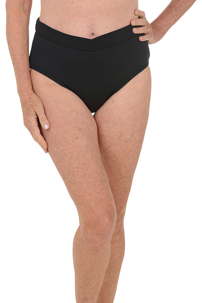 Person wearing black high-waisted bikini bottoms on a white background