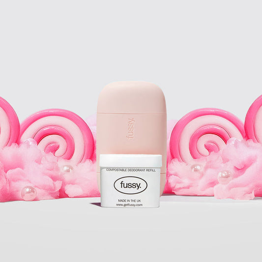 Fussy's Sugar Crush Starter Deodorant Pack featuring a Pale Pink case and one refill pack set against a backdrop of cotton candy and pink and white lollipops