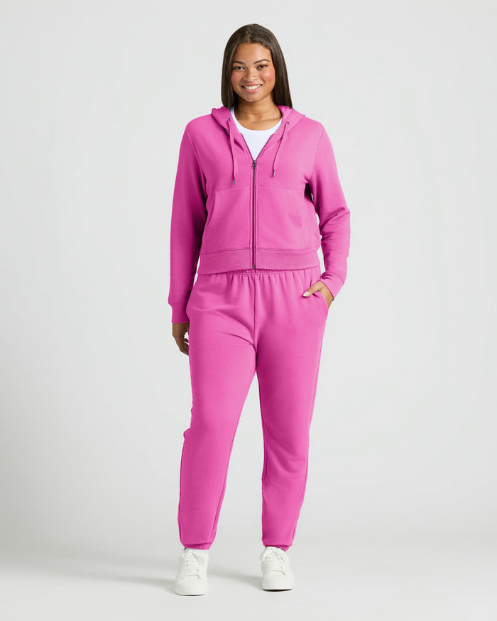 Woman in Womens Electric Fuchsia Crop Zip Hoodie, smiling with hand in pocket.